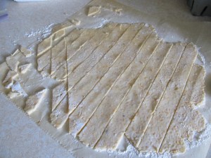 Roll the dough to 1/8th inch and cut into shapes about 1 inch in size.  I cut these into diagonals.  Note I used parchment paper to roll them out.